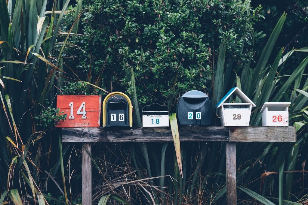 Plusieurs nombres apposés sur des boîtes aux lettres dans un jardin.