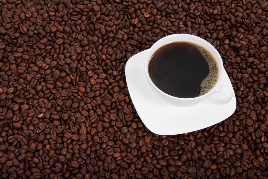 Un café long sur un tapis de grain de café.